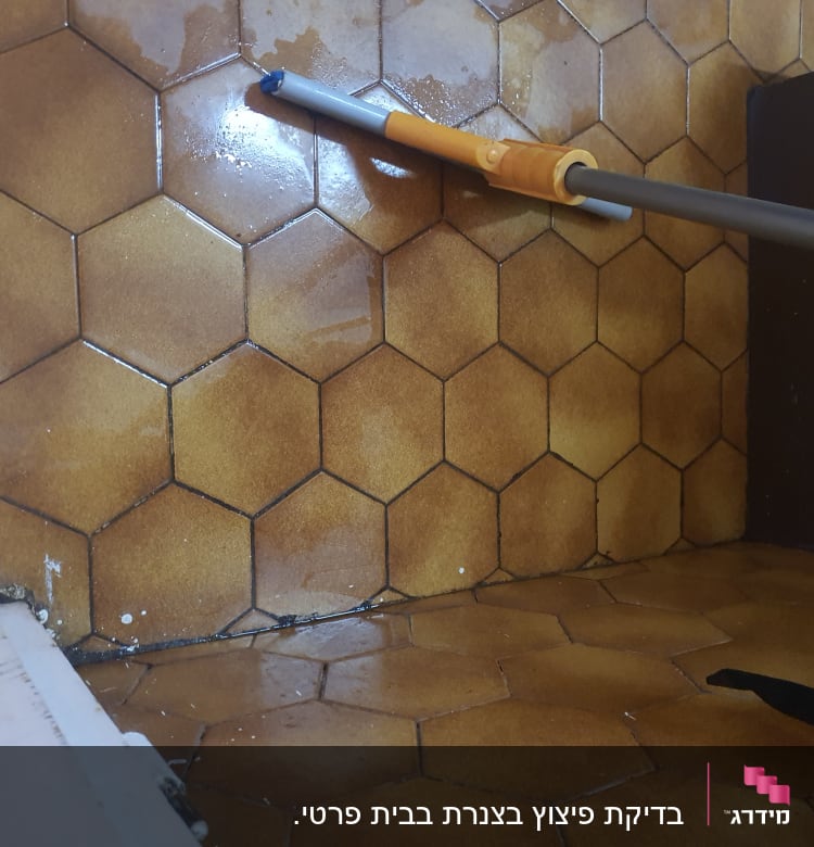 רצפה רטובה עם מגב כתום על אריחים חומים